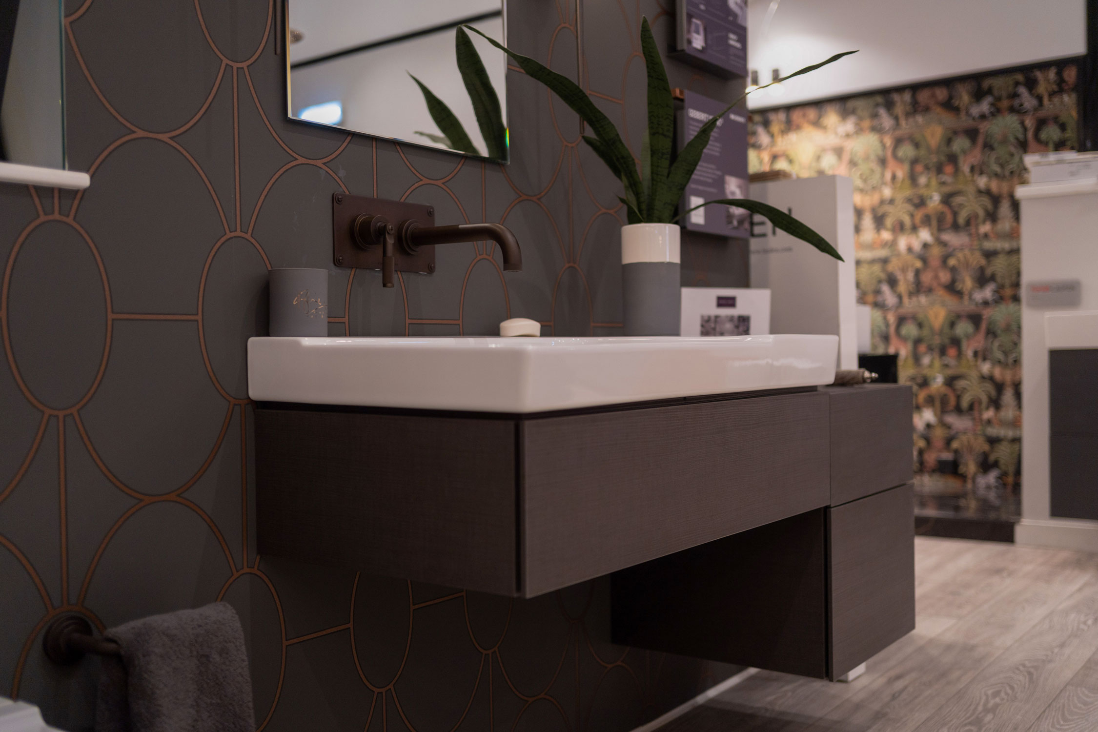 Showroom display of large sink area and brown and grey wallpaper.